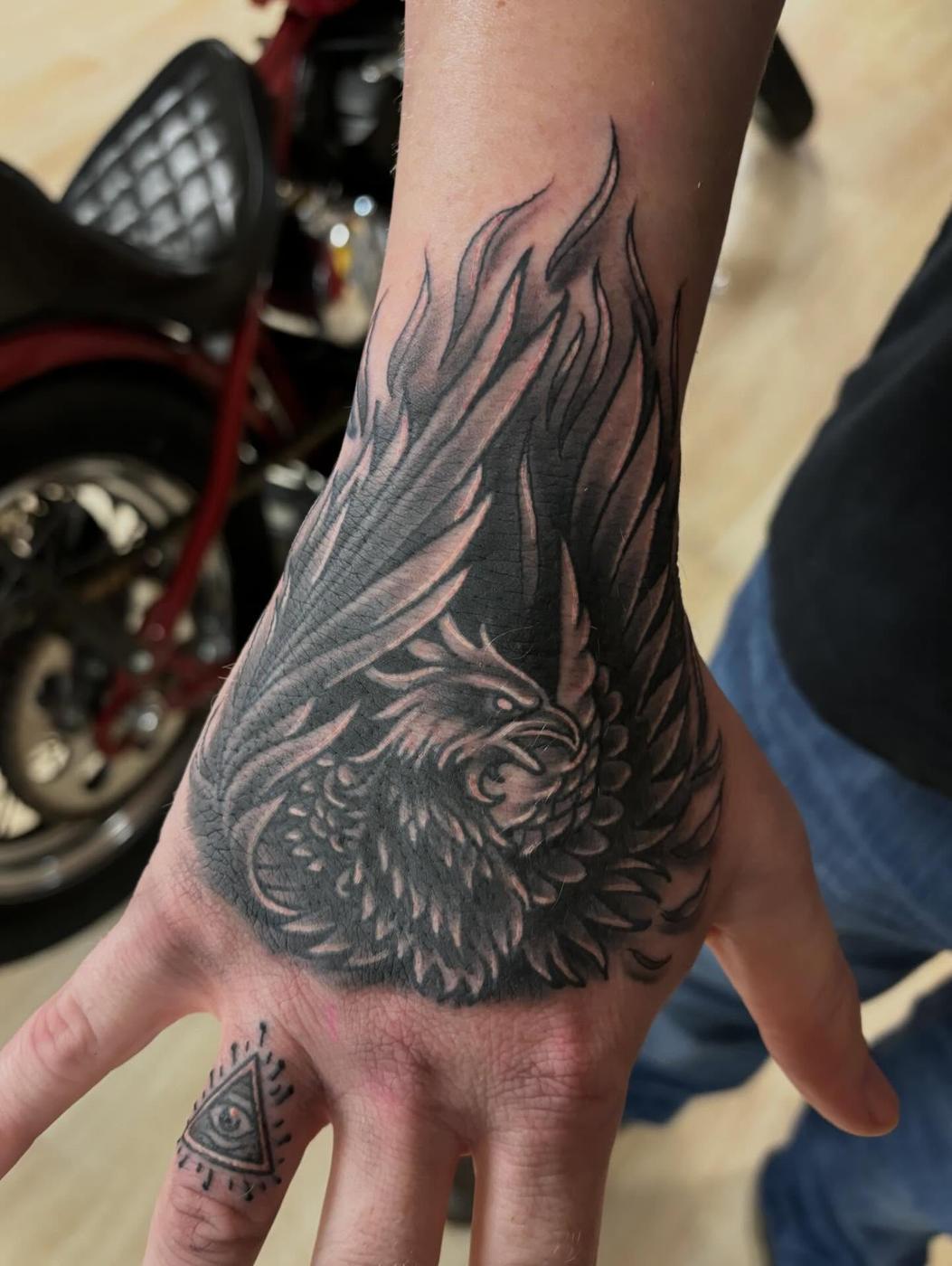 A black and gray eagle tattooed on a hand