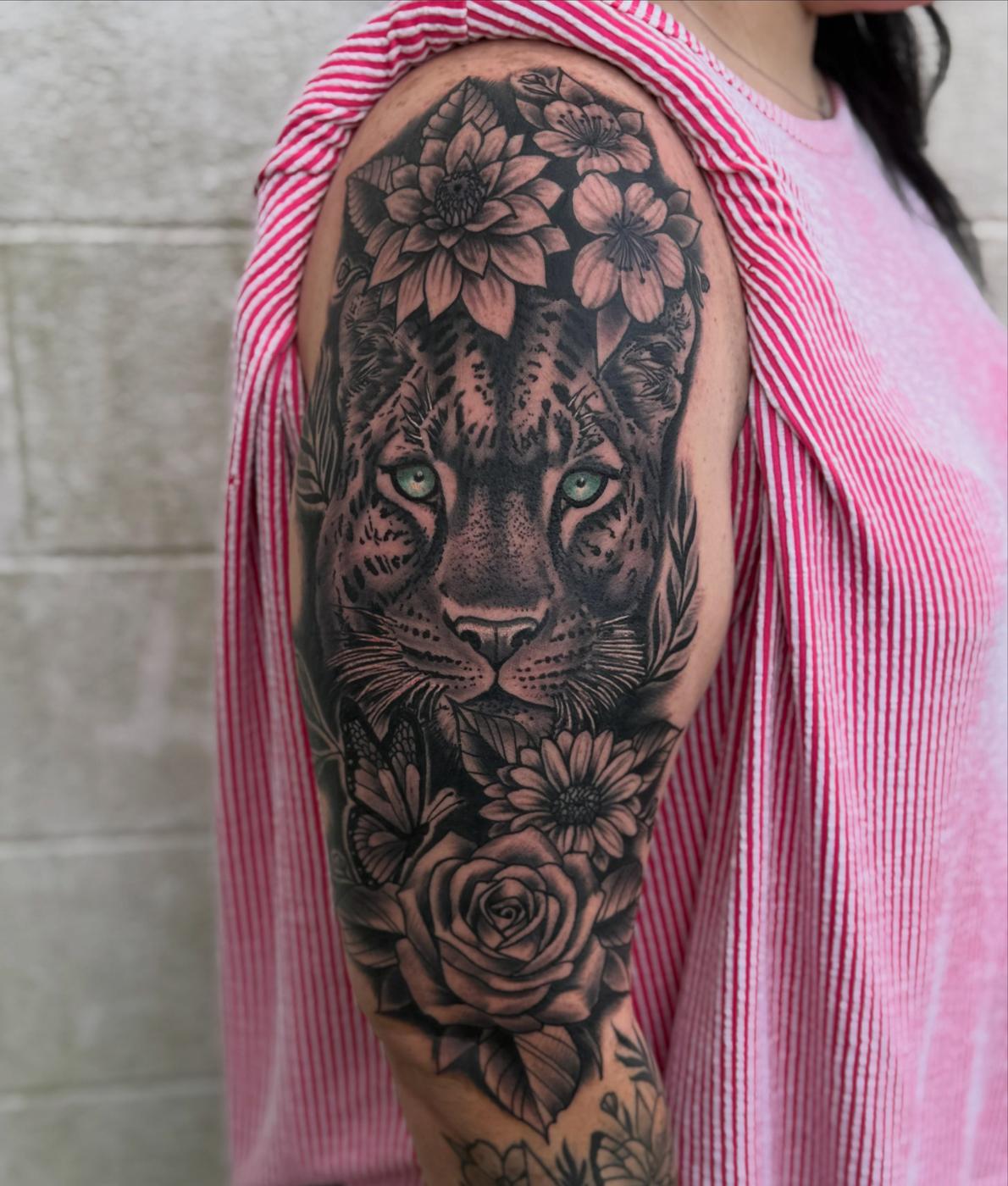A black and gray leopard and florals tattoo on an upper arm