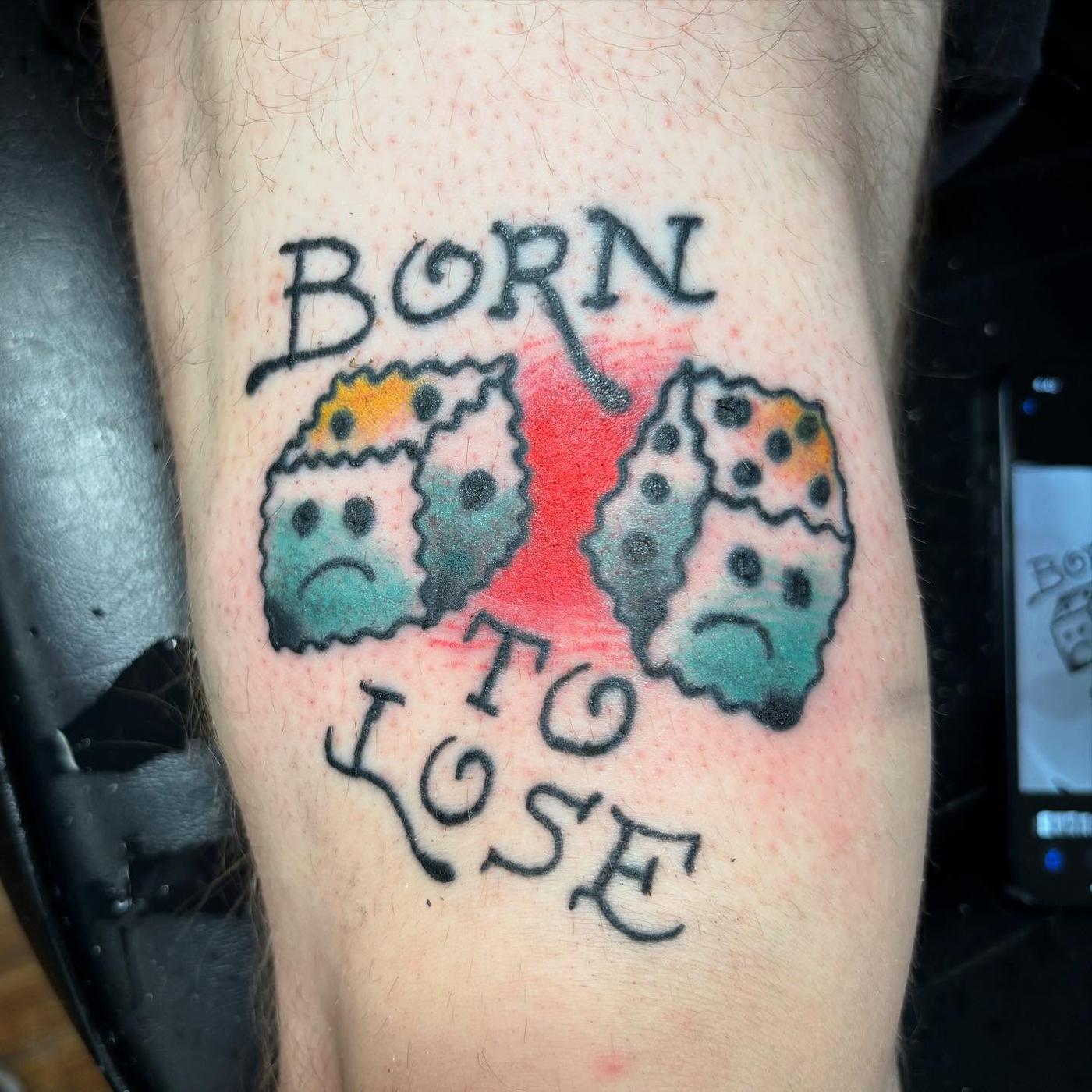 A traditional dice tattoo with lettering reading born to lose