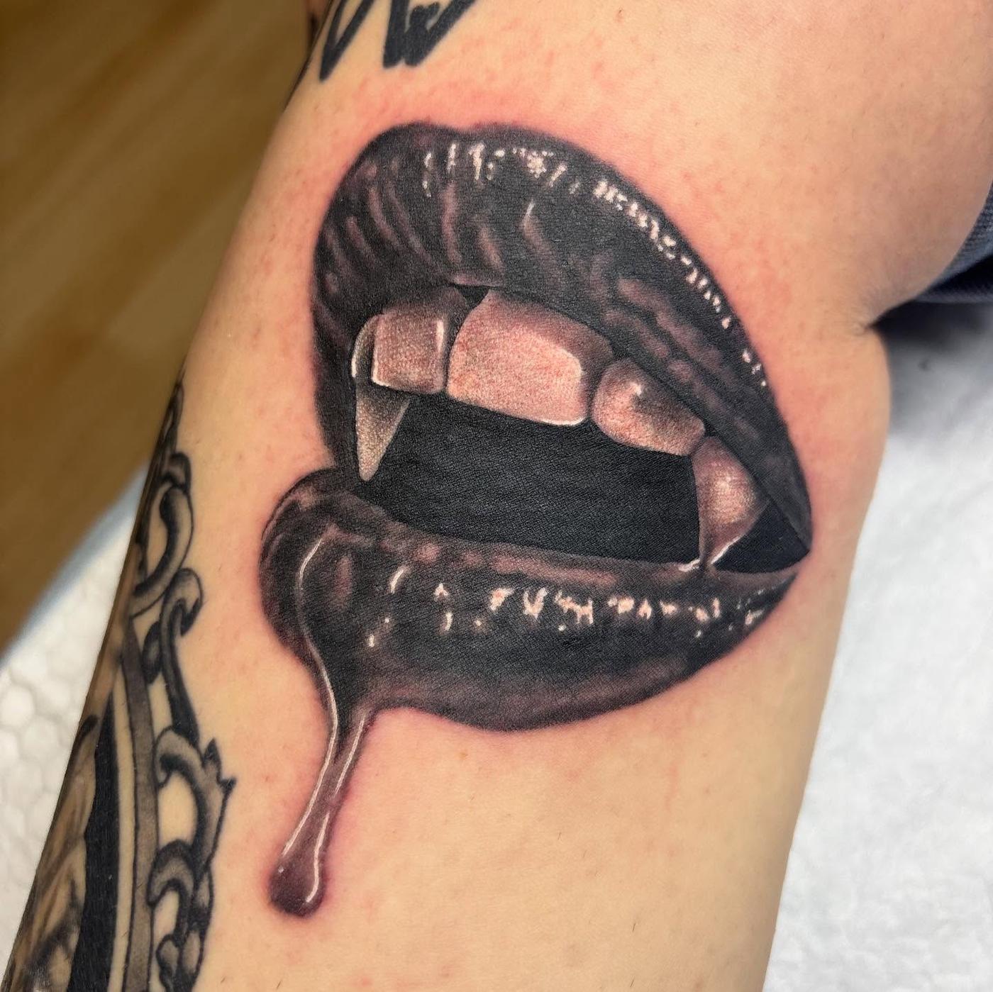 A black and gray realism tattoo of vampire lips