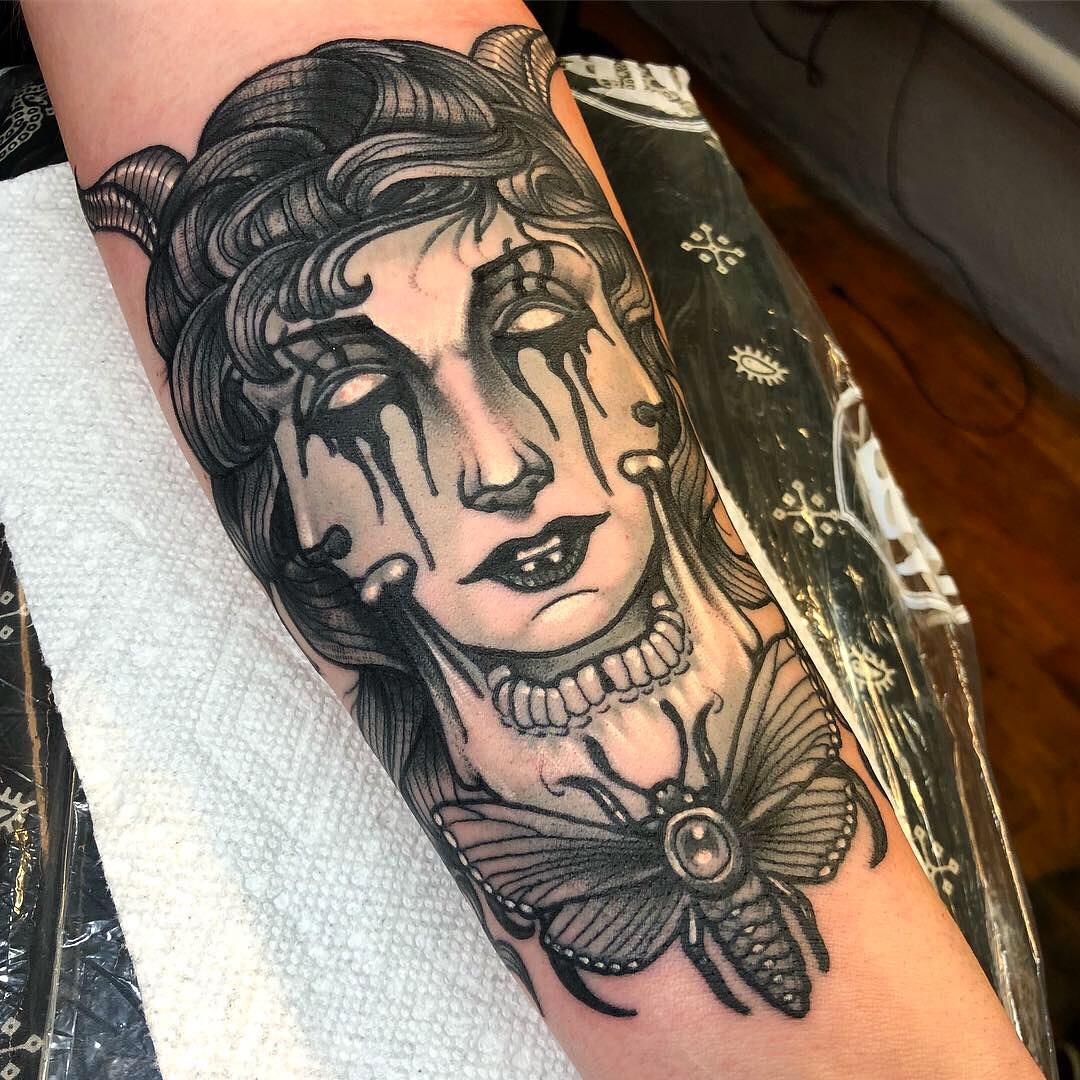 A black and gray neo-traditional tattoo of a woman with a moth